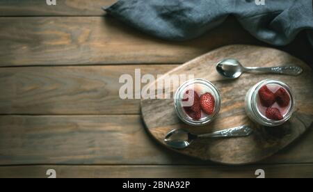 Zwei Gläser Joghurt auf einem Holzständer Stockfoto