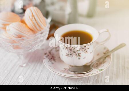 Foto zum Internationalen Tee-Tag. Tasse Tee auf einem Tisch mit Makronen. Monochromatische Farben. Elegantes Image. Internationaler Tee-Tag im Hintergrund. Stockfoto