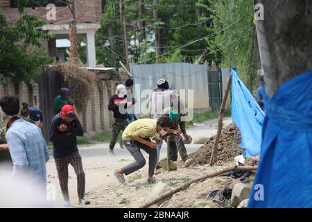 Die Dorfbewohner von Kaschmir laufen um Deckung, als eine von indischen Polizisten abgefeuerte Tränengashülle bei einem Protest gegen die Ermordung eines Zivilisten in Makhama, westlich von Srinagar, im von Indien kontrollierten Kaschmir, am Mittwoch, den 13. Mai 2020, in ihrer Nähe explodiert. Indische Soldaten haben den jungen Mann am Mittwoch an einem Kontrollpunkt in der Himalaya-Region Kaschmir tödlich erschossen, sagten Einwohner und Beamte und lösten in der umstrittenen Region anti-indische Proteste und Zusammenstöße aus. Indiens Central Reserve Police Force sagte, dass der Mann ein Auto fuhr und Signale ignorierte, an zwei Kontrollpunkten im westlichen Stadtrand von Srinagar anzuhalten, der Stockfoto