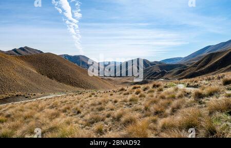 Karge Berglandschaft mit Grasbüscheln, Lindis Pass, Südalpen, Otago, Südinsel, Neuseeland, Ozeanien Stockfoto