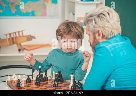 Glücklicher Vater und Sohn. Spiele und Aktivitäten für Kinder. Mann Lehrer spielen Schach mit Vorschulkind Stockfoto