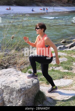 Frau, 40-45 Jahre alt, macht Step-Up-Übung am Isarufer in München, Bayern. Stockfoto