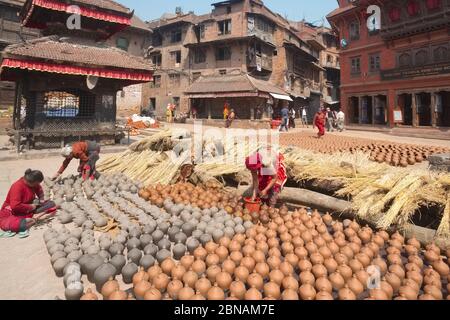 Frauen legen frisch hergestellte Töpferwaren zum Trocknen in der Sonne aus; Pottery Square, Bhaktapur, Kathmandu Valley, Nepal Stockfoto