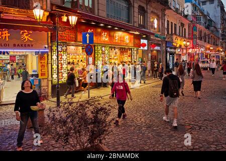 Menschen, die auf der Rua de S. Paulo (Dasanba) Straße in der Nacht beleuchtet. Macau, China. Stockfoto