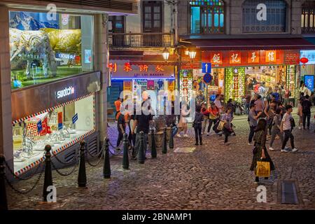 Menschen, die auf der Rua de S. Paulo (Dasanba) Straße in der Nacht beleuchtet. Macau, China. Stockfoto