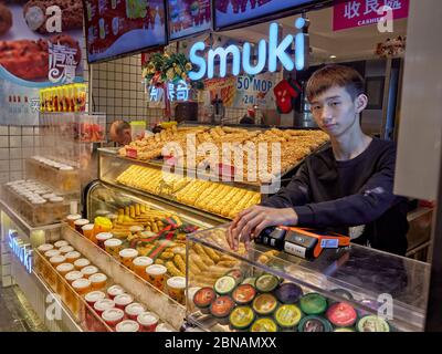 Junger Verkäufer bei Smuki, einem beliebten Dessertstand, der knackiges Baguette mit Sahne auf der Rua de S. Paulo (Dasanba) Straße verkauft. Macau, China. Stockfoto