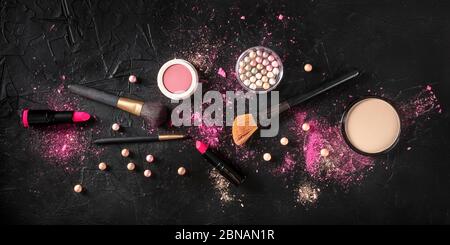 Professionelles Make-up über dem Kopf Panoramafoton auf dunklem Hintergrund. Pinsel, Lippenstift und andere Produkte, eine flache Lage Stockfoto