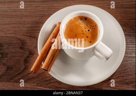 Zimtstangen und Espresso in einem kurzen Glas auf Holzhintergrund Stockfoto