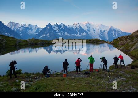 Fotografen bleiben am See und machen Fotos. Traumhafte Berge, orangefarbener Sonnenaufgang in einem wunderschönen Tal. Farbenfrohe Sommeransicht des Lac Blanc Sees Stockfoto