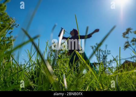 Ein Mädchen spielt Badminton auf einer Lichtung. Sommerzeit. Konzentrieren Sie sich auf das Gras im Vordergrund. Stockfoto