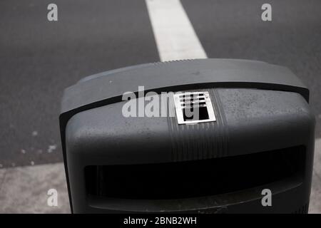 Eine obere Hälfte eines grauen Aschenbezuges entlang des Bürgersteigs mit einem Aschenbecher auf dem oberen Teil. Stockfoto