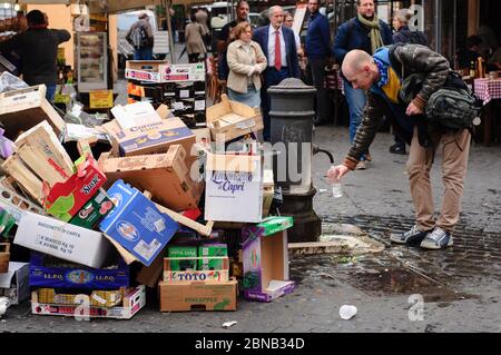 Rom, Italien - 27. Oktober 2015: Mann gießt Wasser in eigene Flasche aus dem städtischen Trinkbrunnen auf dem schmutzigen Marktplatz Campo de Fiori. In der Mitte stehen Stockfoto