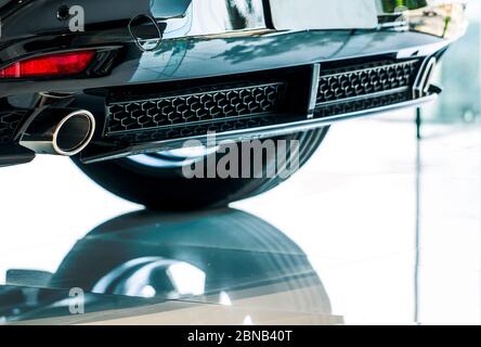 Nahaufnahme Detail Auspuffrohr des Autos, die im Showroom mit Reflexion geparkt. Einzigartiges Muster der Auto Auspuffrohr. Zubehör für Sportwagen. Abluft Stockfoto