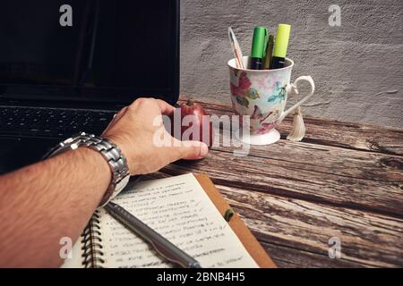 Notebook-Computer Marker und roter Apfel auf dem Holztisch Stockfoto