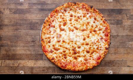 Eine hausgemachte Käse-Pizza sitzt auf einem dekorativen Schneidebrett. Stockfoto