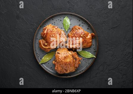 Filipino Chicken Adobo auf dunkelgrauer Platte auf schwarzem Schieferhintergrund. Chicken Adobo ist philippinische Küche Gericht aus geschmorten Hähnchenschenkel, Sojasauce, Vinega Stockfoto