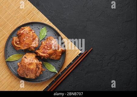 Filipino Chicken Adobo auf dunkelgrauer Platte auf schwarzem Schieferhintergrund. Chicken Adobo ist philippinische Küche Gericht aus geschmorten Hähnchenschenkel, Sojasauce, Vinega Stockfoto