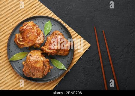 Filipino Chicken Adobo auf dunkelgrauer Platte auf schwarzem Schieferhintergrund. Chicken Adobo ist philippinische Küche Gericht aus geschmorten Hähnchenschenkel, Sojasauce, Vinega Stockfoto