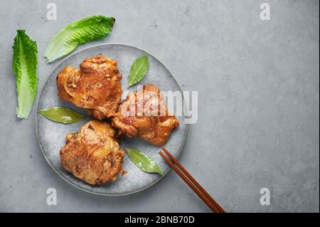 Filipino Chicken Adobo auf grauer Platte auf Betonhintergrund. Chicken Adobo ist philippinische Küche Gericht aus geschmorten Hähnchenschenkel, Sojasauce, Essig, schwarz Stockfoto