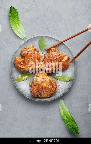 Filipino Chicken Adobo auf grauer Platte auf Betonhintergrund. Chicken Adobo ist philippinische Küche Gericht aus geschmorten Hähnchenschenkel, Sojasauce, Essig, schwarz Stockfoto