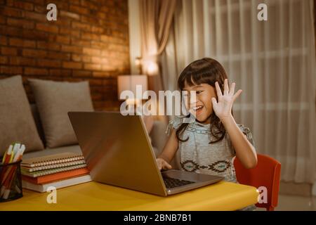 Kleines Kind Videoanrufe mit Laptop zu Hause am Abend mit der Lehrerin Stockfoto