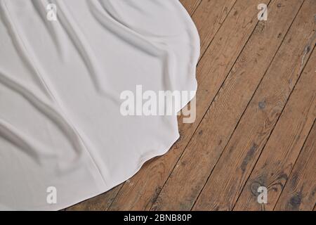 High-Angle-Aufnahme des Zuges der weißen Hochzeit Kleiden Sie sich auf dem Holzboden Stockfoto