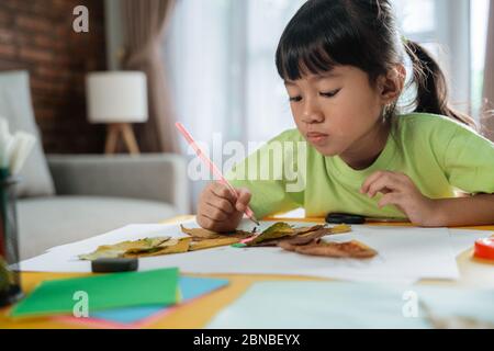 Kind macht Kunst aus trockenen Blättern zu Hause von selbst. Stockfoto