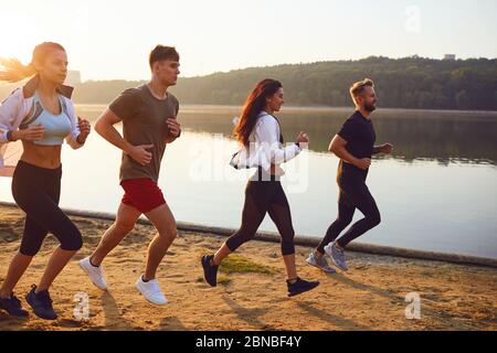 Eine Gruppe junger Sportler läuft in einem Park am See. Stockfoto