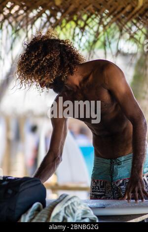 Surfer waxing das Surfbrett vor dem Paddeln in Hikkaduwa, Sri Lanka Stockfoto