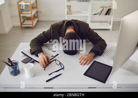 Geschäftsmann in einer Jacke müde erschöpft von Stress-Probleme liegen am Arbeitsplatz im Büro. Stockfoto