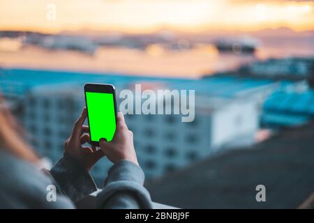 Frau, die Fotos mit einem Smartphone auf dem grünen Bildschirm aufnimmt Stockfoto