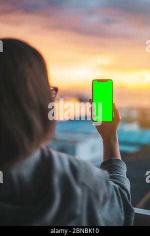 Frau, die ein Smartphone auf einem grünen Bildschirm hält Stockfoto