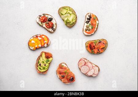 Hausgemachte Sandwiches mit Brot und verschiedenen Zutaten und Gewürzen auf einem hellen Hintergrund. Gesunde und leckere Speisen zum Frühstück und Mittagessen Stockfoto