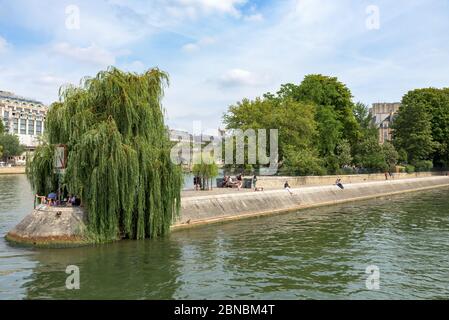 Paris, Frankreich. Blick auf die Menschen, die am Ufer der seine in der Ile de la Cite, in der Nähe von Pont Neuf und Square du Vert-Galant sitzen und sich sonnen. Stockfoto