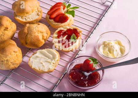 Leckeres Frühstück von Scones mit gerinnter Sahne und Erdbeermarmelade auf rosa Hintergrund, Draufsicht Stockfoto