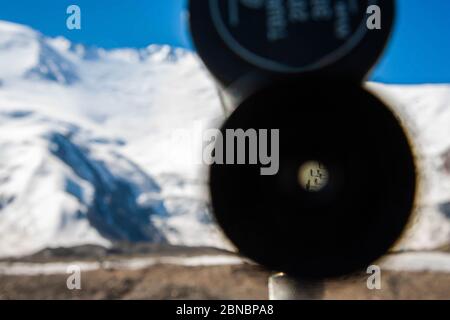 Ansicht einer Gruppe von Bergsteigern durch ein Lupenglas-Teleskop. Landschaftlich reizvolle Landschaft mit schneebedeckten Berggipfeln. Stockfoto