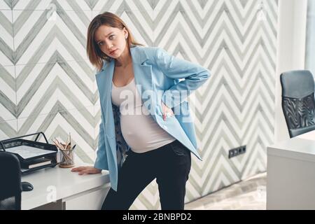 Verärgert schwangere Dame Gefühl Schmerzen im Rücken bei der Arbeit Stockfoto