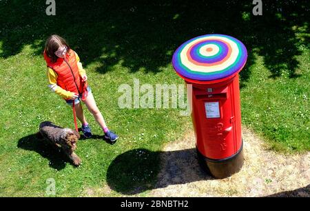 Loughborough, Leicestershire, Großbritannien. Mai 2020. Ein Mädchen geht mit ihrem Hund an einer Royal Mail Briefbox vorbei, die in Regenbogenfarben bombardiert wurde, um die Unterstützung für Schlüsselarbeiter während der Sperrung der Coronavirus-Pandemie zu zeigen. Credit Darren Staples/Alamy Live News. Stockfoto