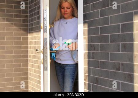 Junges Mädchen desinfiziert die Türklinke in der Wohnung Stockfoto