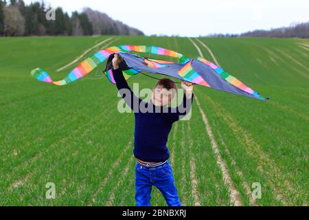 Boy startet einen Drachen in einem Feld im Frühjahr. Stockfoto