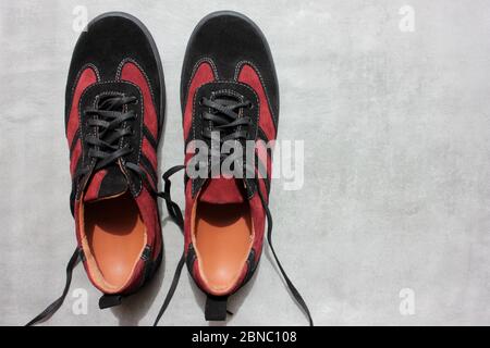 Ein Paar orthopädische Sportschuhe auf einem grauen Betongrund mit Kopierraum. Nahaufnahme von burgunderroten Sneakers aus Wildleder von oben Stockfoto