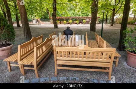 München, Deutschland. Mai 2020. Ein Mann sitzt allein auf einer der 12 eng angeordneten Bänke im Biergarten am Wienerplatz. Ab dem 18. Mai, nach der Corona-Pause, darf die Gastronomie in Bayern wieder die Freiflächen und Biergärten öffnen. Quelle: Peter Kneffel/dpa/Alamy Live News Stockfoto