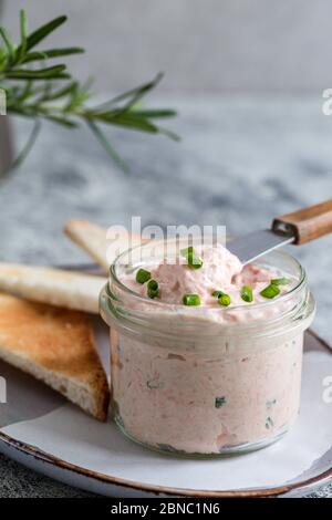 Lachs und weicher Cremekäse im Glas. Lachsrilletten, Mousse, Pastete und Toasts auf grauem Hintergrund Stockfoto