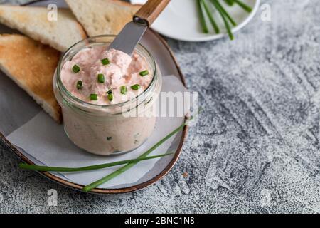 Lachs und weicher Cremekäse im Glas. Lachsrilletten, Mousse, Pastete und Toasts auf grauem Hintergrund Stockfoto