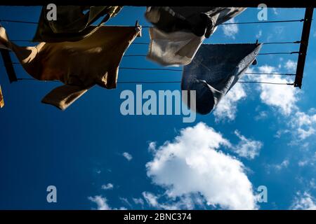 Kleidung wird auf dem Wind auf Hintergrund blauen Himmel und Wolken getrocknet. Stockfoto