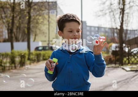 POSEN, POLEN - Apr 17, 2020: Junger sechs Jahre alter polnischer kaukasischer Junge, der Seife erzeugt. Blasen. Stockfoto