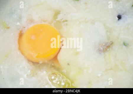 Reisbrei mit Schweinefleisch, das Eigelb auf der Schüssel auffüllen kann Stockfoto