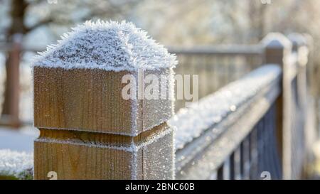 Schwere Nachtfrost auf Holzpfosten auf Zaun um Gartenterrasse gebildet. Nahaufnahme von Eispartikeln. Stockfoto