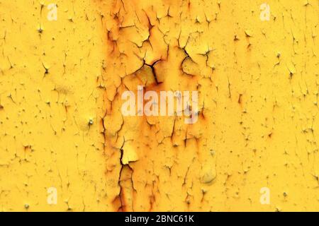 Wand mit gelber abblätternder Farbe mit Rissen und Rost. Flecken auf einer lackierten Oberfläche. Alternde verwitterte Textur. Stockfoto