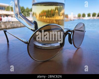 Sonnenbrille und eine Tasse Bier auf dem Tisch Stockfoto